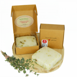 Thyme soap bars with cardboard packaging and a thyme sprig on a wooden stand, product photo