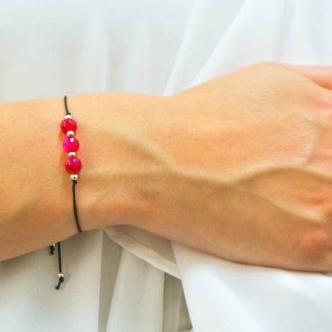 Pink agate friendship bracelet on adjustable black cord with small silver details, worn on wrist