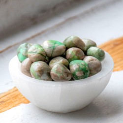 Variscite pocket stones in a white bowl on a wooden surface